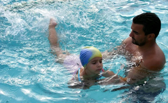 O fetiţă este deprinsă cu apa de un instructor profesionist
