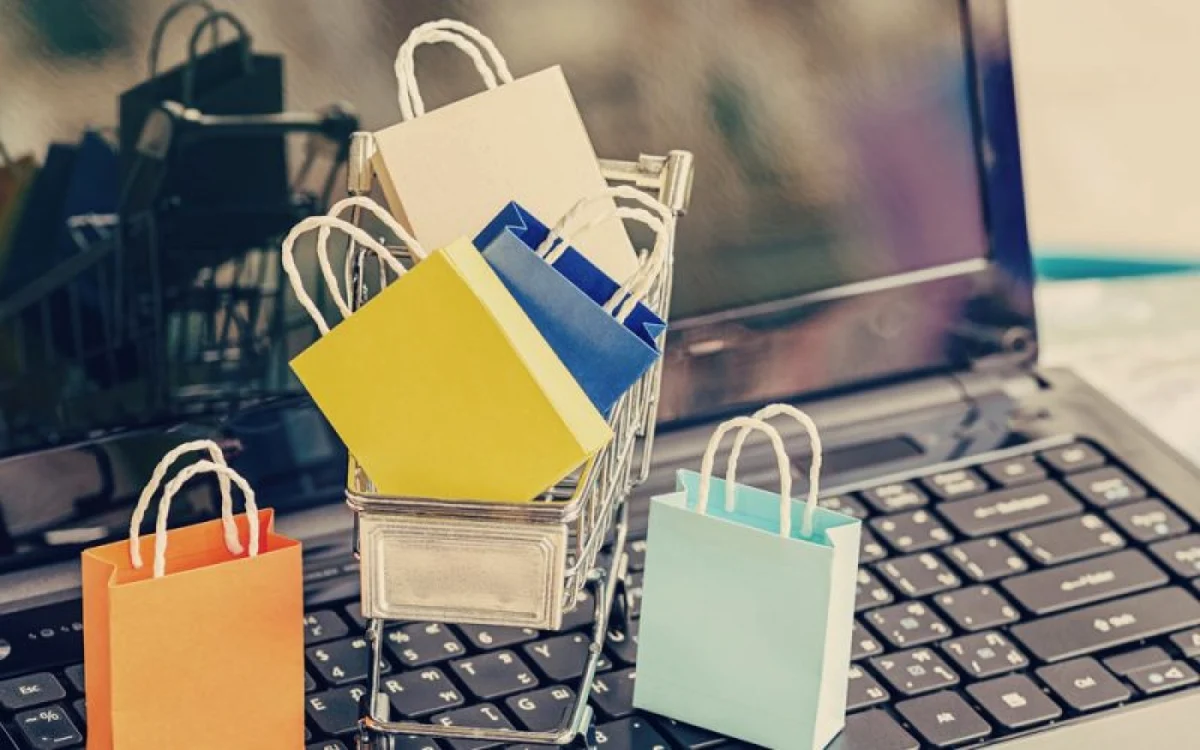 Un laptop pe care sunt așezate mici pungi de cadouri sugerând comerțul online
