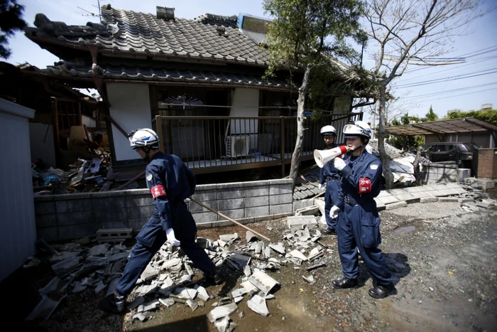 Poliţişti strigă după oamenii care ar putea fi prinşi sub dărâmături lângă o casa lovită de cutremur în Mashiki prefectura Kumamoto sudul Japoniei FOTO AP