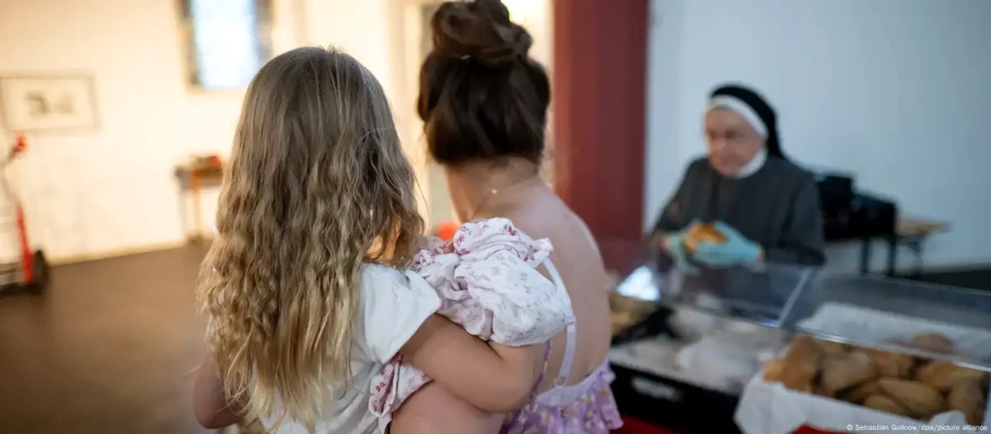 Fetița Emilya, în brațele mamei ei în timp ce aceasta primește ajutoare de la o bancă de alimente
