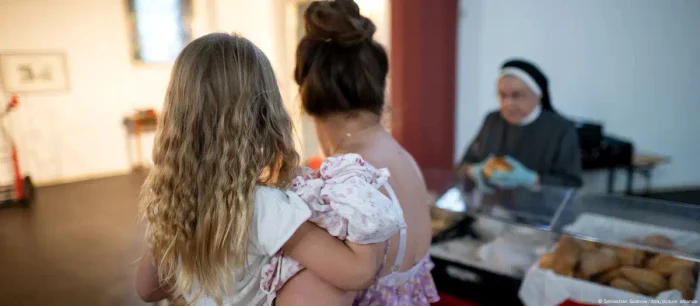 Fetița Emilya, în brațele mamei ei în timp ce aceasta primește ajutoare de la o bancă de alimente
