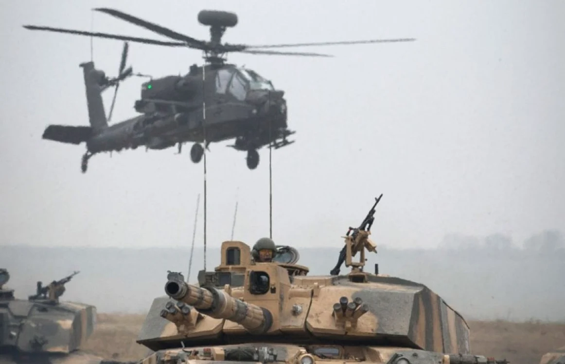 Elicoptere Apache zboară deasupra unei coloane de vehicule blindate din regimentul  Yorks and Kings Royal Hussars care iau parte la  Exercise Tractable în  Salisbury Anglia FOTO Guliver/Getty Images