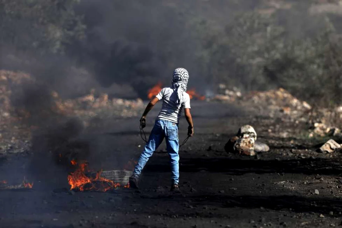 Un protestatar Palestinian priveşte către soldaţii israelieni în timpul ciocnirilor în Qadomem din satul Kofr Qadom din West Bank FOTO EPA-EFE / Alaa Badarneh
