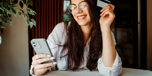 Tânără cu un card si telefon - cheltuie bani FOTO Shutterstock 
