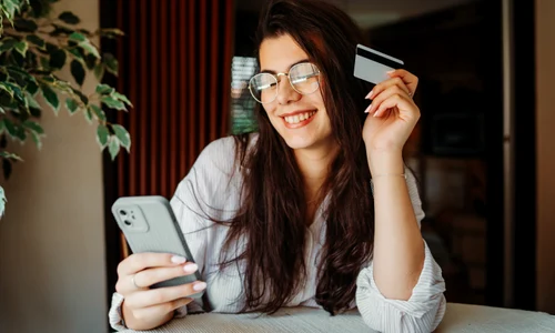 Tânără cu un card si telefon - cheltuie bani FOTO Shutterstock