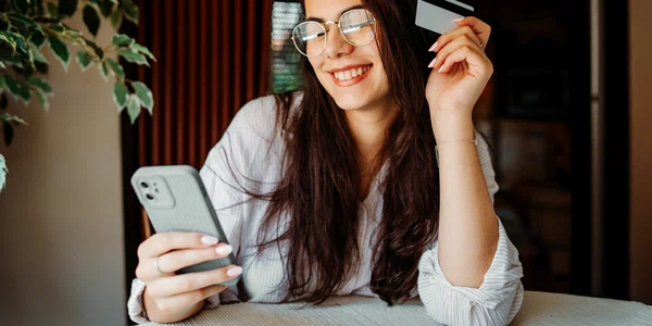 Tânără cu un card si telefon - cheltuie bani FOTO Shutterstock 