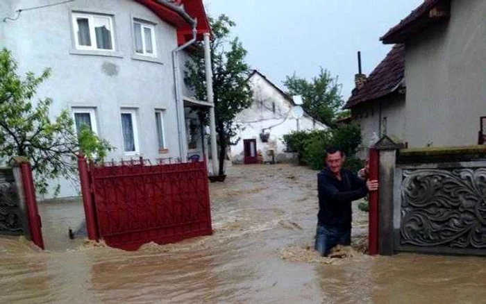 Un localnic încearcă să traverseze prin apa care îi inundă curtea. FOTO: ISU Hunedoara.