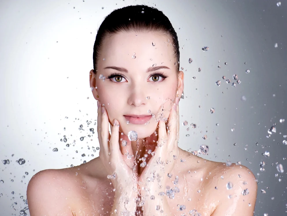 Femeie admirând stropii de apă care o înconjoară în timpul rutinei de îngrijire Midwest Dermatology