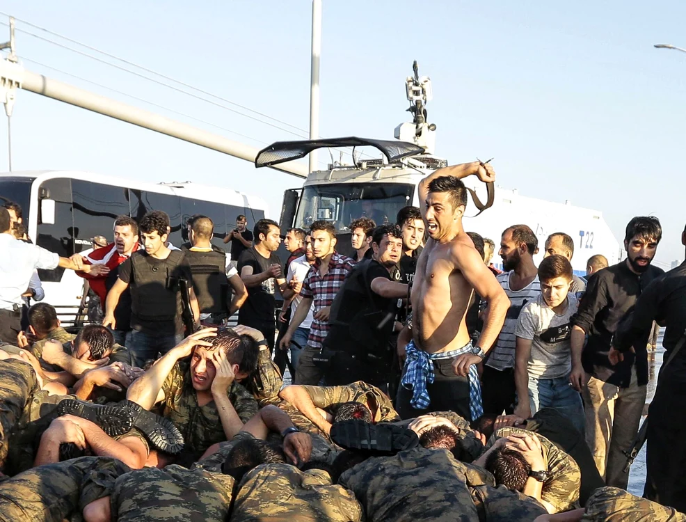 
    Un protestatar îi lovește cu cureaua pe soldații puciști care stăteau în genunchi cu mâinile deasupra capuluiFoto: Getty Images  