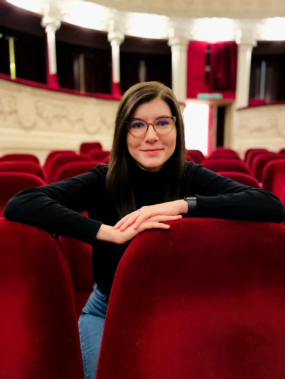 Regizoarea Teodora Petre, pe scaun, într-o sală de teatru goală