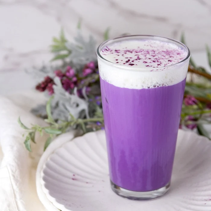Pahar cu o băutură lăptoasă de cuâloare mov numită ube latte