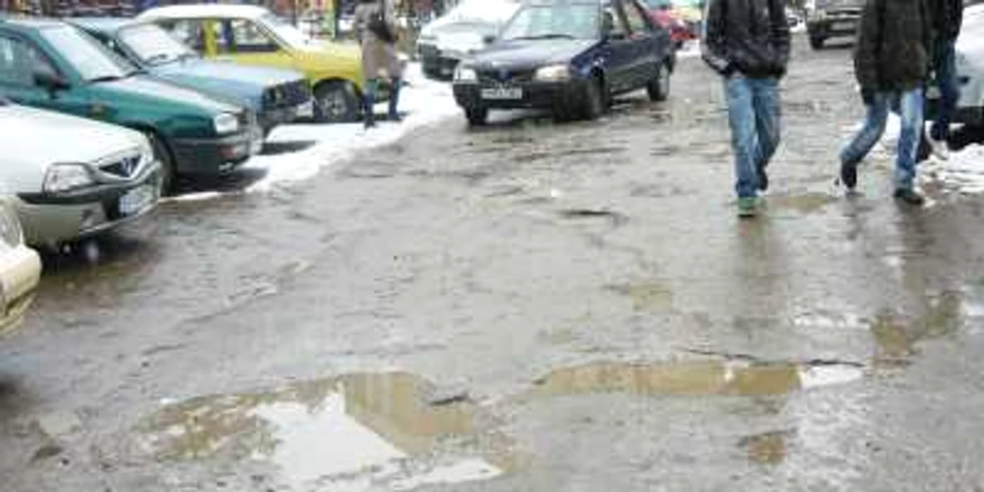 Gropile de pe strada Oituz le macină nervii atât şoferilor, cât şi pietonilor care trebuie să facă slalom printre bălţi