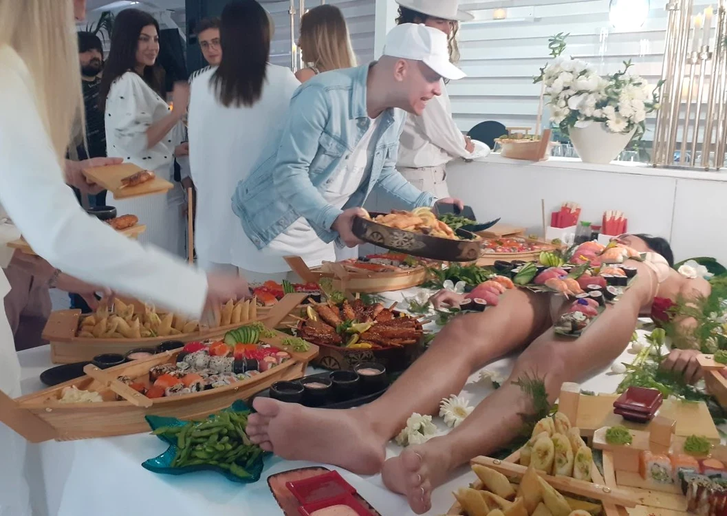 Un invitat o întreabă pe fată cât poate să reziste așa, după care o hrănește cu sushifoto: Click!