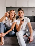 curious couple sitting grey sofa indoor portrait man woman watch tv jpg