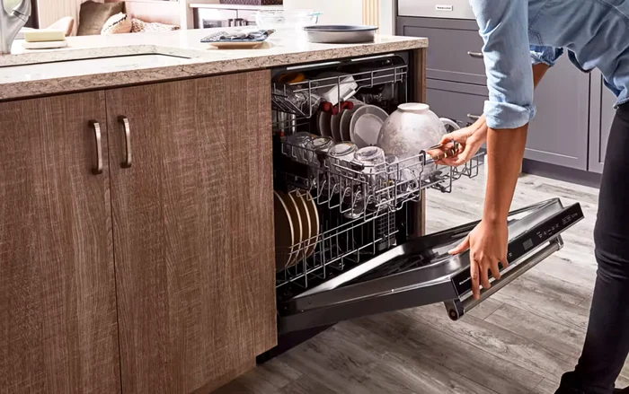 Un bărbat se pregătește să scoată vesela din mașină de spălat vase încorporabilă Sursă IKEA 