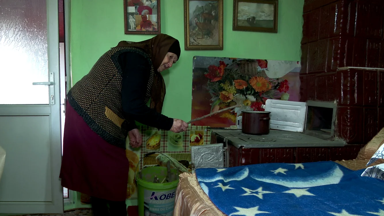 Doamna Stana încălzește soba cu crengi. FOTO Iulian Bunilă