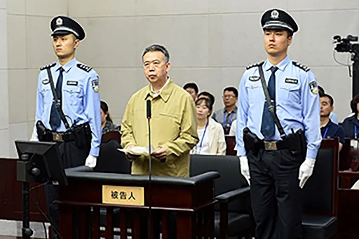 Fostul sef al Interpol Meng Hongwei, flancat de politisti intr-un tribunat din Tianjin FOTO AFP