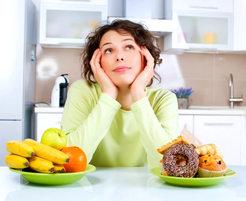 Beautiful Young Woman choosing between Fruits and Sweets jpeg