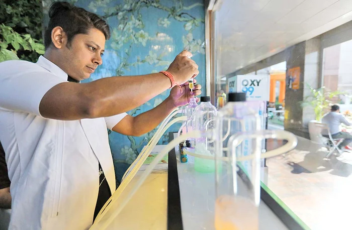 Un barman specializat în ”cocteiluri cu oxigen” prepară recipientele care vor fi livrate la domiciliul clientului