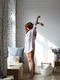 full lenght shot attractive young redhead female long striped shirt standing barefooted her toes bedroom stretching body raising arms facing big window enjoying warm spring sunlight jpg