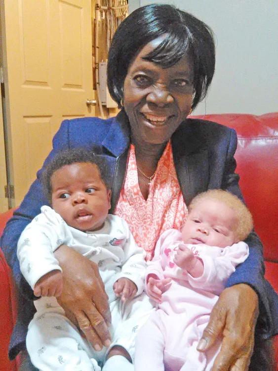 O bunică fericită cu nepoţii alb-negru în braţe 