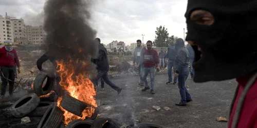 Palestinieni care aruncă cu pietre ard cauciucuri în timpul ciocnirilor cu soldaţii israelieni după rugăciunea de vineri în oraşul Ramallah din West Bank FOTO EPA-EFE / Atef Safadi