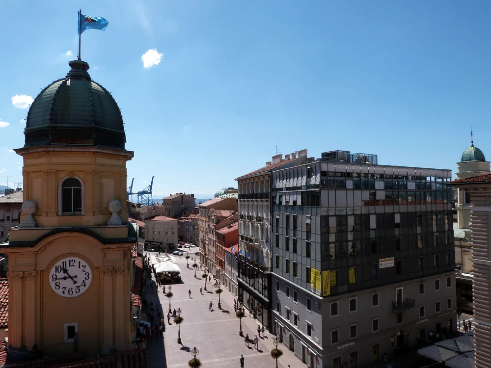 Turn cu ceas și cupolă verde, surprins deasupra unei străzi pietonale din orașul Rijeka, Croația