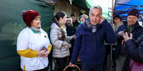 Călin Georgescu, însoțit de soția Cristela Georgescu, personal de pază și reprezentanți ai unui post de televiziune, face cumpărături în Piața 16 Februarie, în București. FOTO Inquam Photos / Octav Ganea