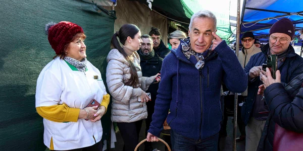 Călin Georgescu, însoțit de soția Cristela Georgescu, personal de pază și reprezentanți ai unui post de televiziune, face cumpărături în Piața 16 Februarie, în București. FOTO Inquam Photos / Octav Ganea