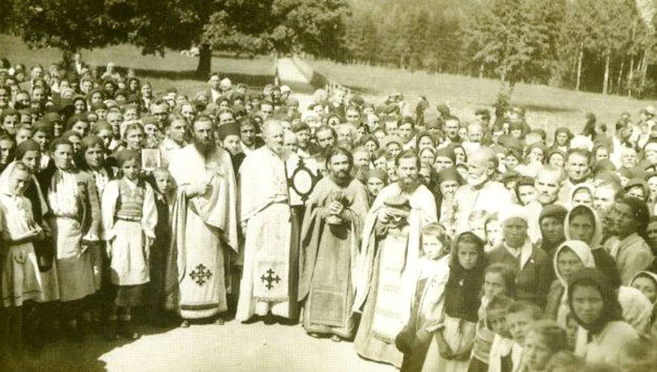 Părintele Arsenie Boca, cu o cruce în mână, alături de alţi preoţi şi de credincioşi