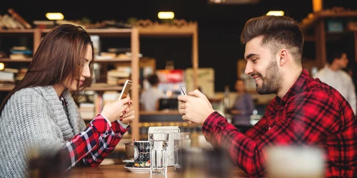 Cuplu la masă scrolează pe smartphone FOTO shutterstock jpg