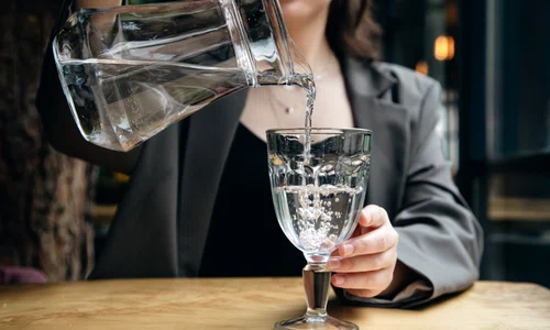 closeup woman pours water into glass cafe jpg
