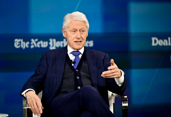 Bill Clinton, stând pe scaun într-un costum albastru