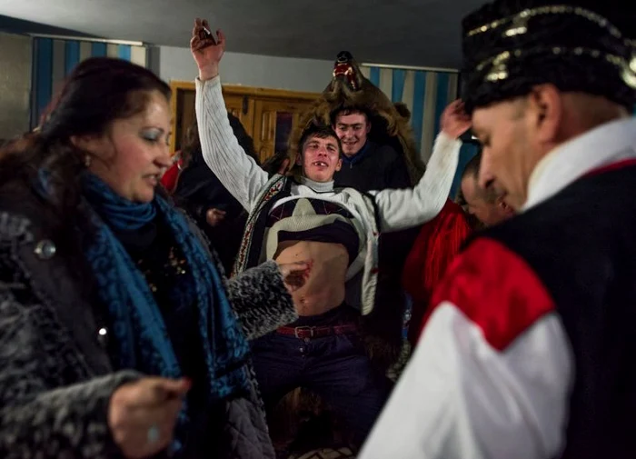 Bărbaţii costumaţi în piei de urs dansează în casele oamenilor