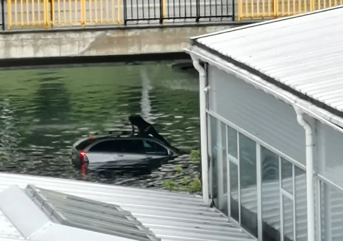 Şoferul s-a suit pe capota maşinii aflate sub ape. FOTO: Dan