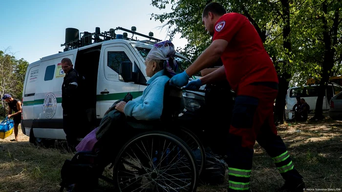 Un voluntar ajută o femeie să se evacueze în regiunea Donețk