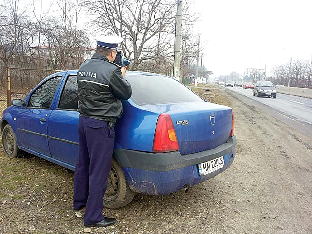
    Polițistul stă cu  pistolul-radar  ascuns după mașina  neinscripționată   