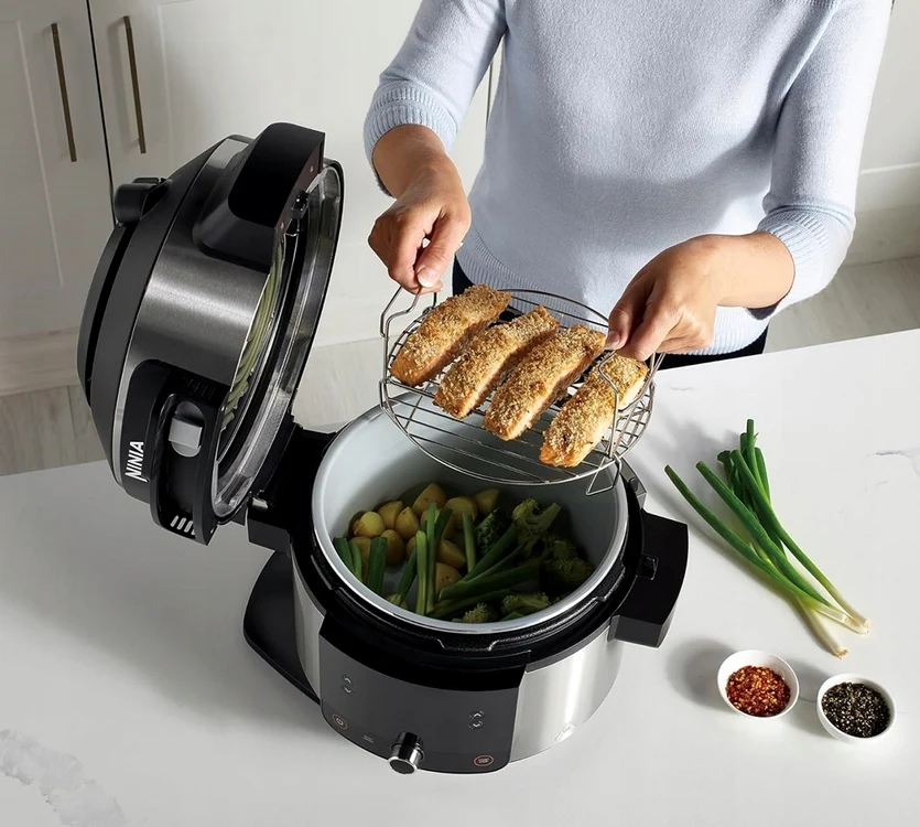 Femeie care gătește mai multe tipuri de mâncare într-un multicooker Sursă eMAG