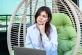 serious young woman works laptop while sitting hammock jpg