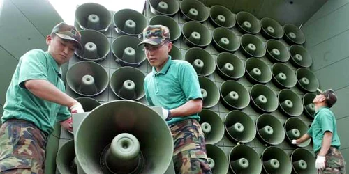 soldati din coreea de sus indeparteaza difuzoarele folosite pentru propaganda la granita cu coreea de nord