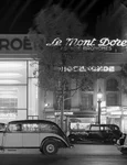 Mașini pe Champs-Élysées, cu showroom-ul Citroën iluminat în fundal, în perioada interbelică. Fotografie de Willem van de Poll (© Nationaal Archief)