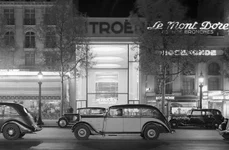 Mașini pe Champs-Élysées, cu showroom-ul Citroën iluminat în fundal, în perioada interbelică. Fotografie de Willem van de Poll (© Nationaal Archief)