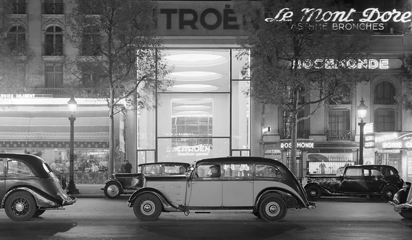 Mașini pe Champs-Élysées, cu showroom-ul Citroën iluminat în fundal, în perioada interbelică. Fotografie de Willem van de Poll (© Nationaal Archief)