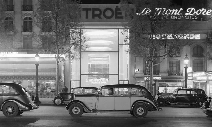 Mașini pe Champs-Élysées, cu showroom-ul Citroën iluminat în fundal, în perioada interbelică. Fotografie de Willem van de Poll (© Nationaal Archief)