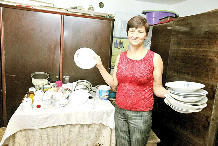 Gospodina casei spală câte  un morman de vase 