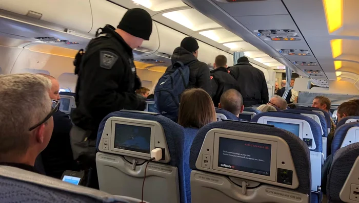 Pasager escortat de poliție. Sursa: CBC