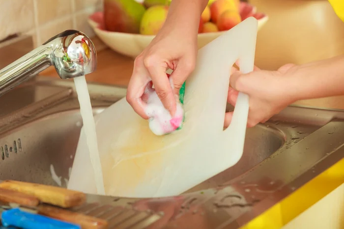 Tocător de plastic spălat în chiuvetă cu apă și detergent Foto Cooking Panda