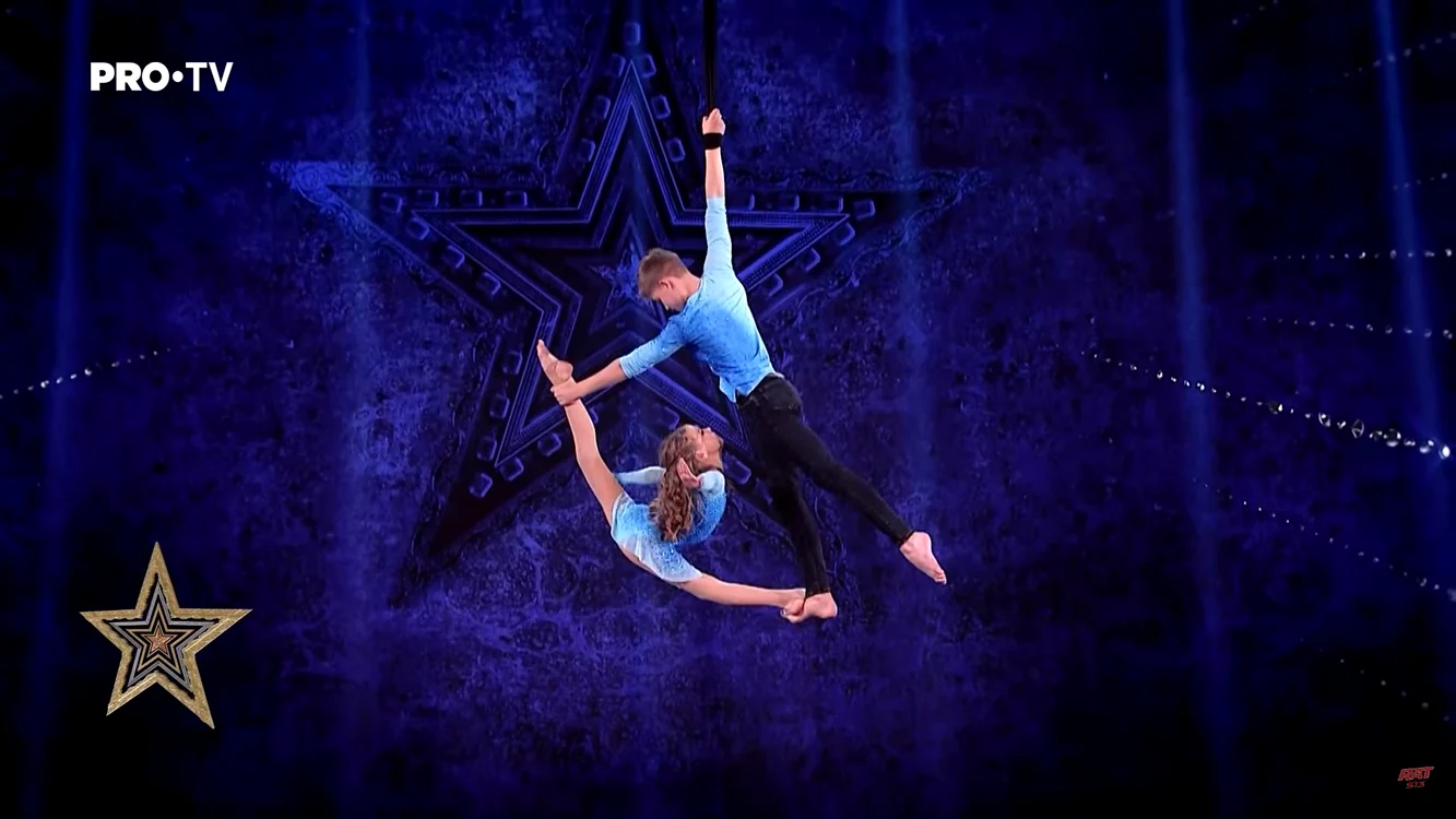 Doi gimnaști fac acrobații cu o coardă