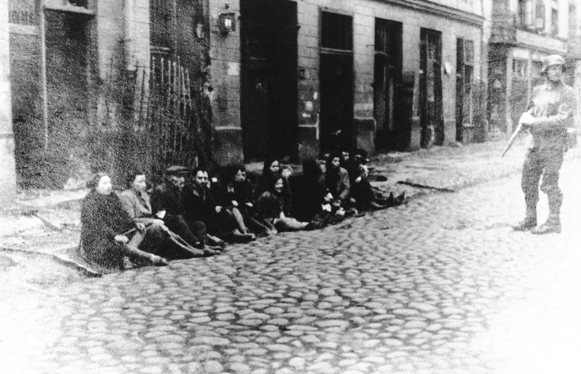 Evrei polonezi puși la pământ și supravegheați de un soldat nazist