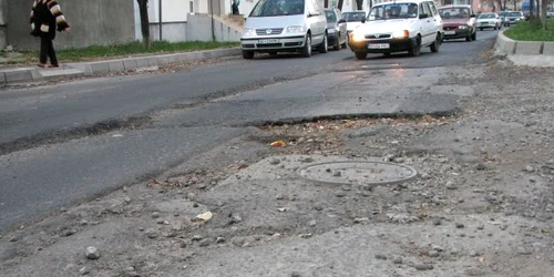 Şoferii şi pietonii trebuie să facă slalom printre gropi.